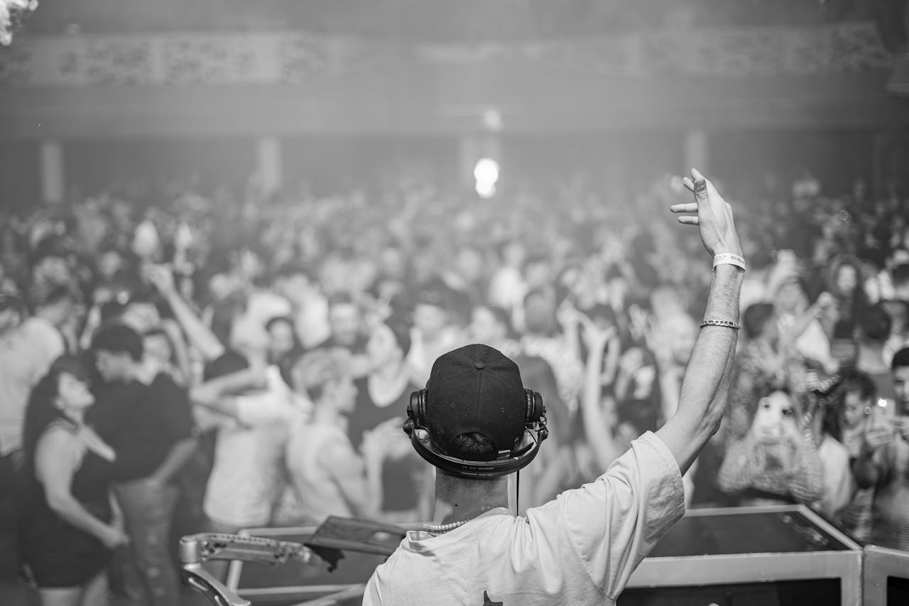 Rhythm of the afterlife DJ in control, hyping up a large crowd at a lively nightclub event, creating an electrifying atmosphere.